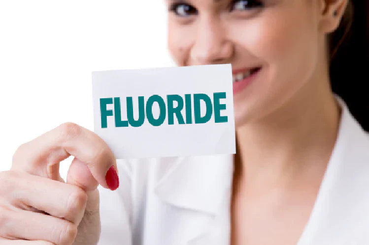 Une image d'une femme tenant un carton avec du fluor écrit dessus.