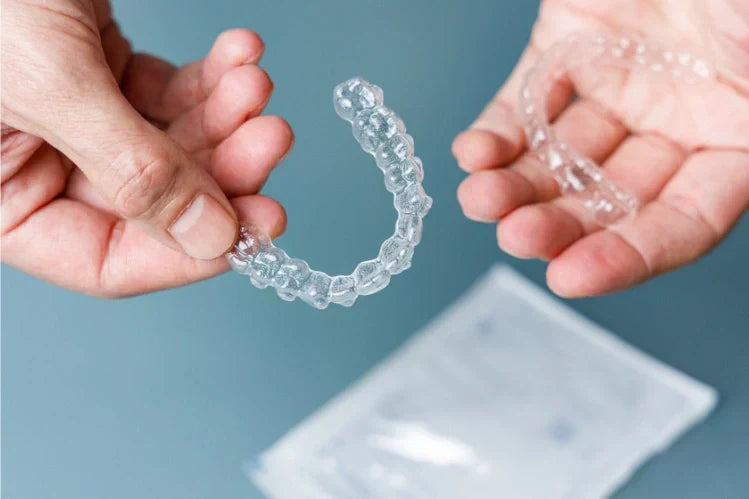 Mains tenant une paire d'aligneurs transparents
