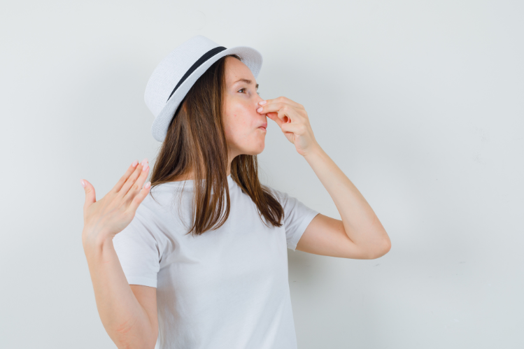 Une jeune fille se pince le nez à cause d'une mauvaise odeur
