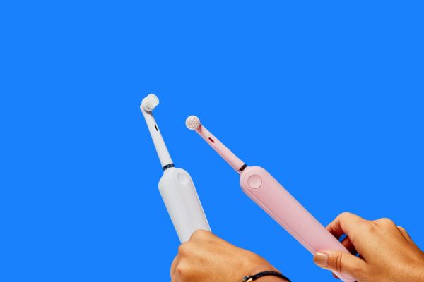 Brosses à dents électriques blanches et roses sur fond bleu