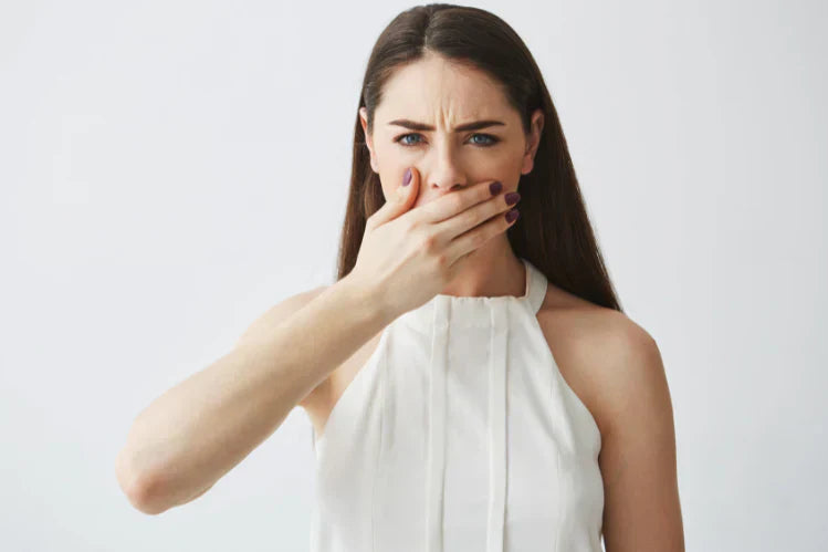 Une femme se couvre la bouche, gênée.