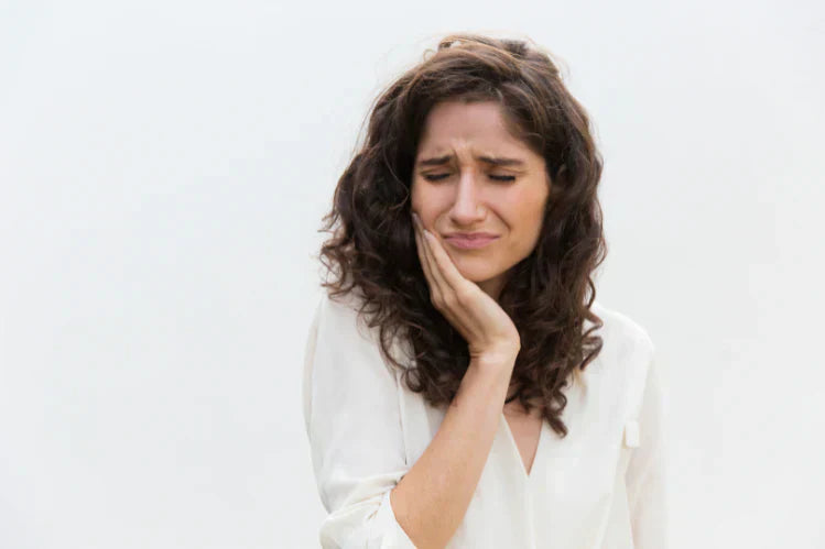 Une femme se tient la mâchoire à cause d'un mal de dents.